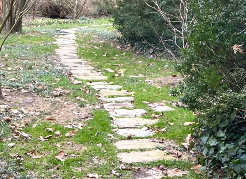 a stone path meanders around a corner to symbolize a garden calling you to more